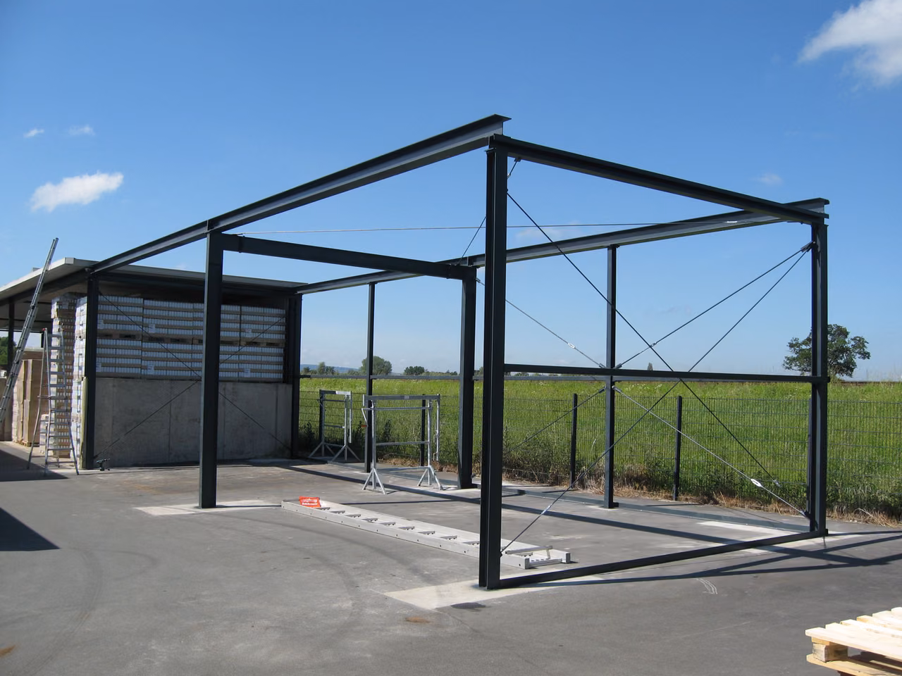 Stahlrahmen einer großen Überdachung vor einem Feld
